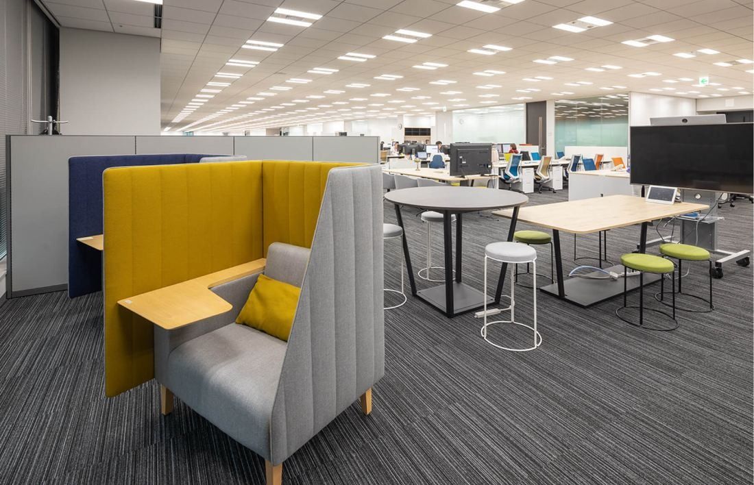 SEGA: Yellow high-backed armchair and round tables in an open work area