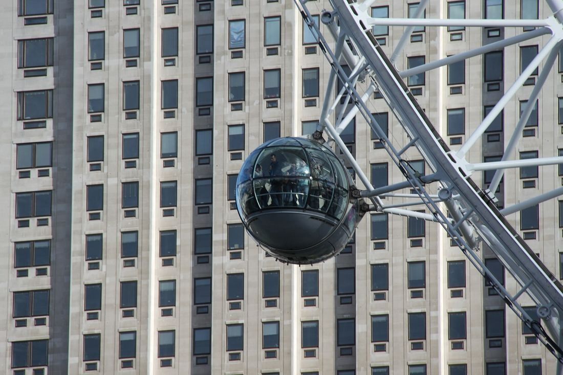 Shell: A glass capsule of the observation wheel passing in front of the tower's window grid