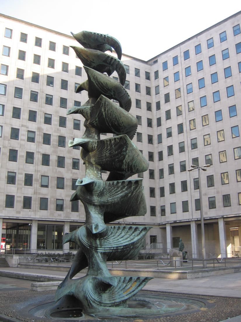 Shell: Bronze fountain sculpture of stacked shell and wave forms in front of a white office facade