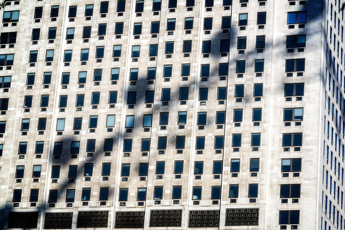 Shell: Close view of the tower's rows of windows with the curved shadow of a large observation wheel across the facade