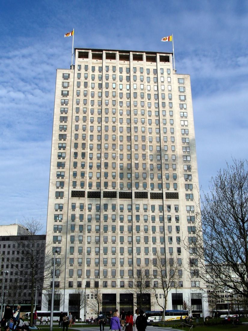 Shell: Looking up at the tower's grid of windows from its base, with bare winter branches to one side