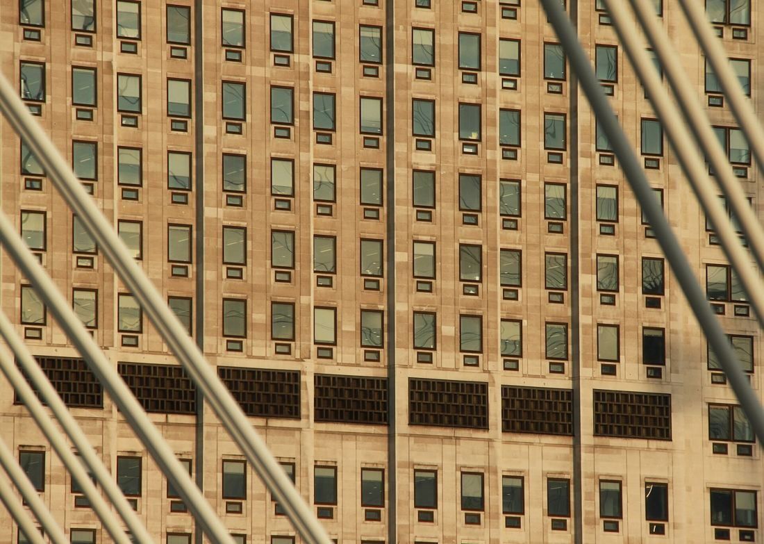 Shell: Pale stone facade with regular rows of windows seen through the white steel spokes of the observation wheel