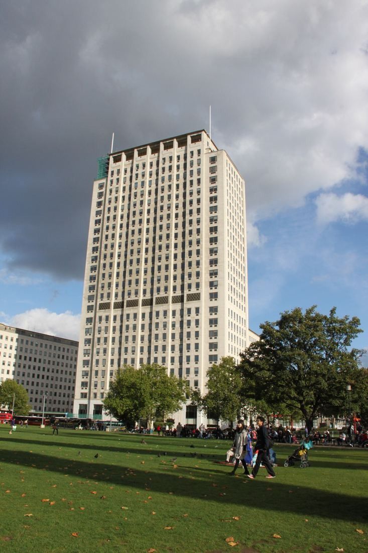 Shell: Tower above a sunny lawn with trees and a few distant people