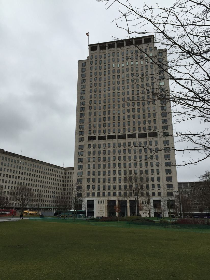 Shell: Tower and a lower wing beyond an open lawn on an overcast day