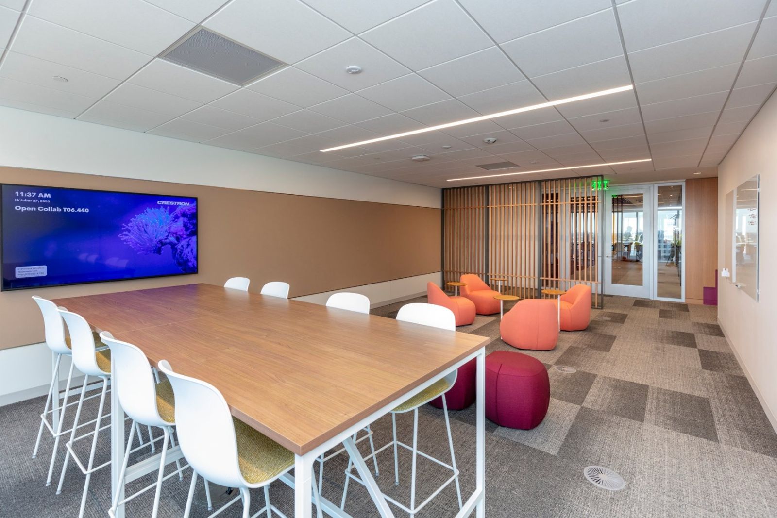 Sherwin-Williams: Collaboration space with a high table, pink stools and a video screen