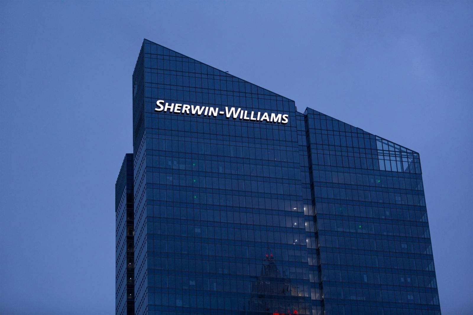 Dark glass tower with the Sherwin-Williams name at the top at dusk