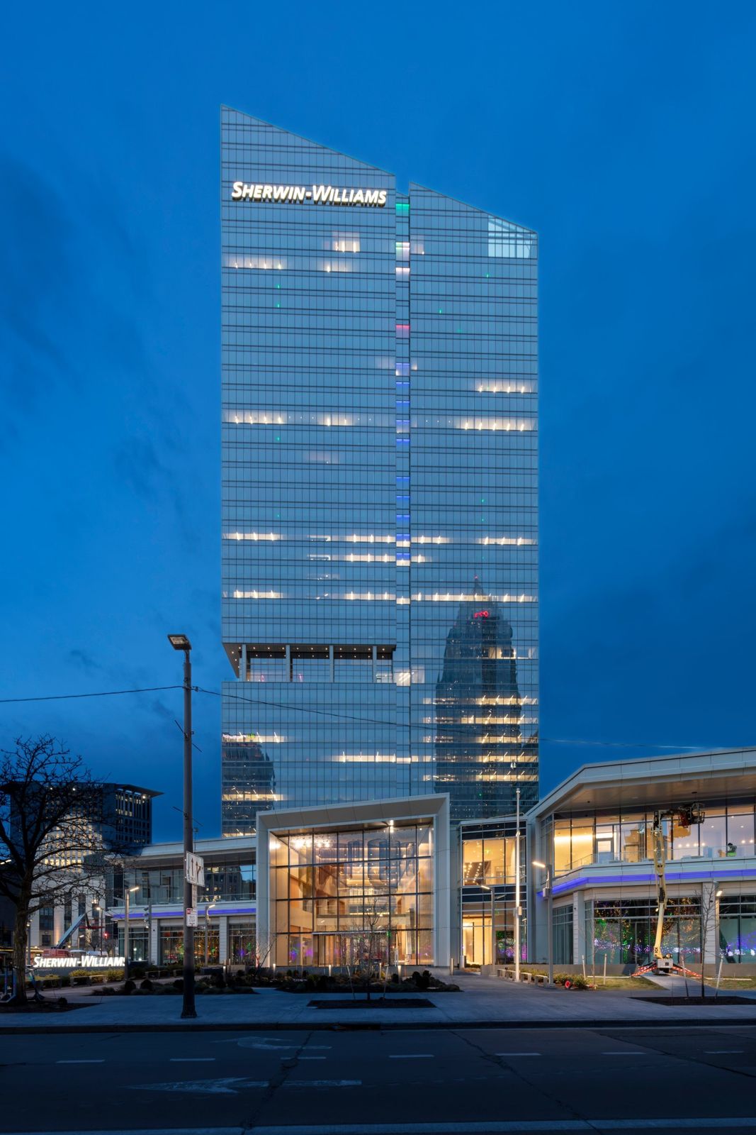 Sherwin-Williams: Glass tower and low pavilion lit at dusk