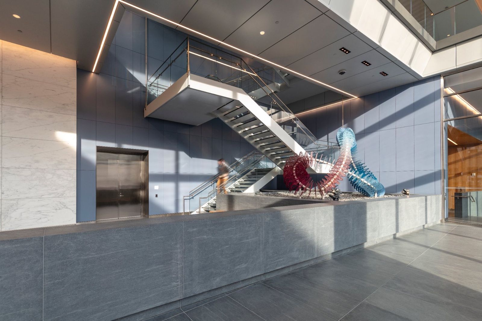 Sherwin-Williams: Lobby with a stone wall, a steel stair and a colorful sculpture
