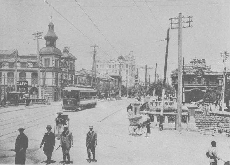 Old photograph of a wide Ginza street with trams, rickshaws and Western-style buildings