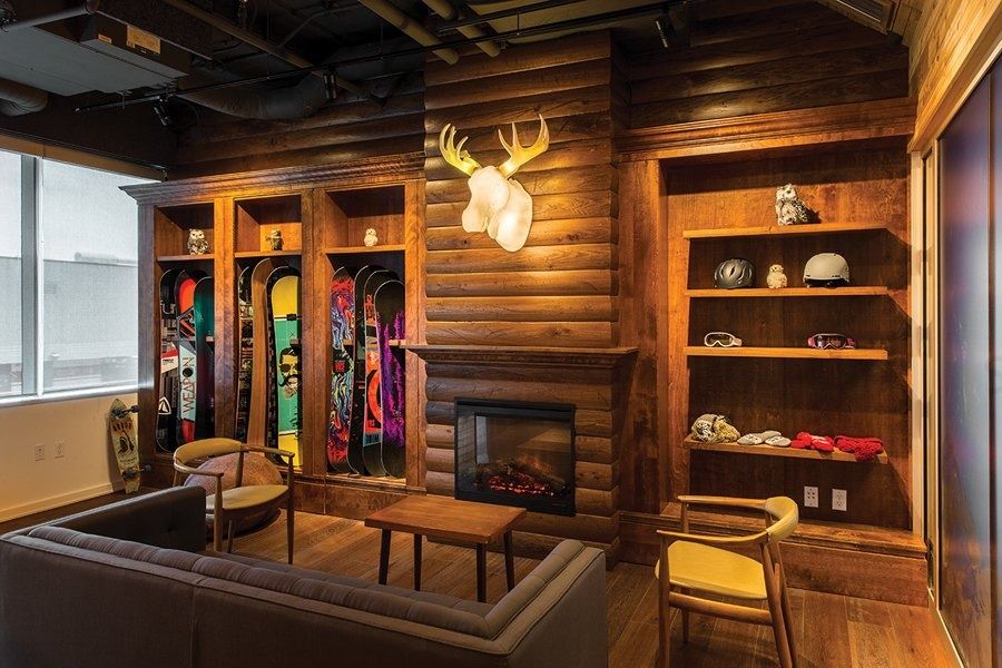 A log-cabin lounge with a fireplace and snowboards, Shopify Ottawa