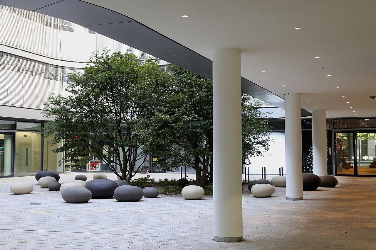 Arcade with columns opening onto a courtyard with trees and stone seats