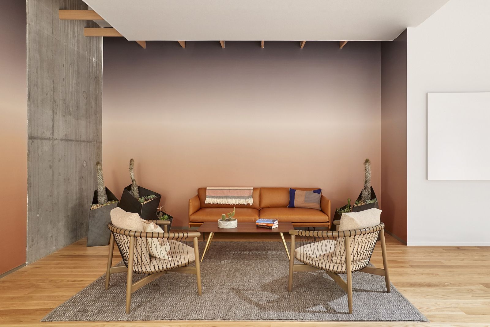 Lounge with leather sofa and rattan chairs against a peach wall