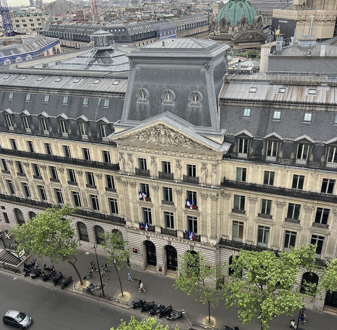 Société Générale: Aerial view of a long stone facade with a carved pediment and trees along the boulevard