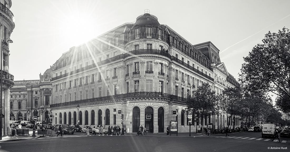 Société Générale: Black-and-white photo of the domed stone corner building with sunlight flaring over the roof