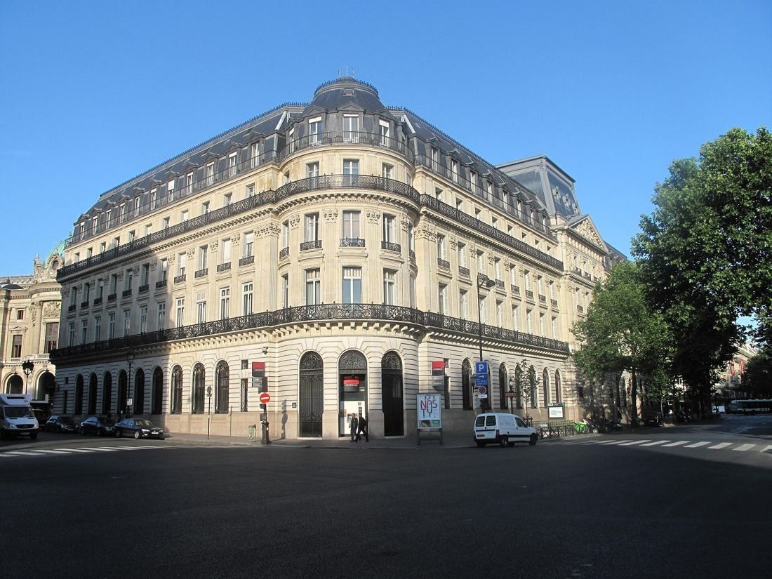 Société Générale: Cream stone corner building with a slate mansard roof and small dome under a blue sky