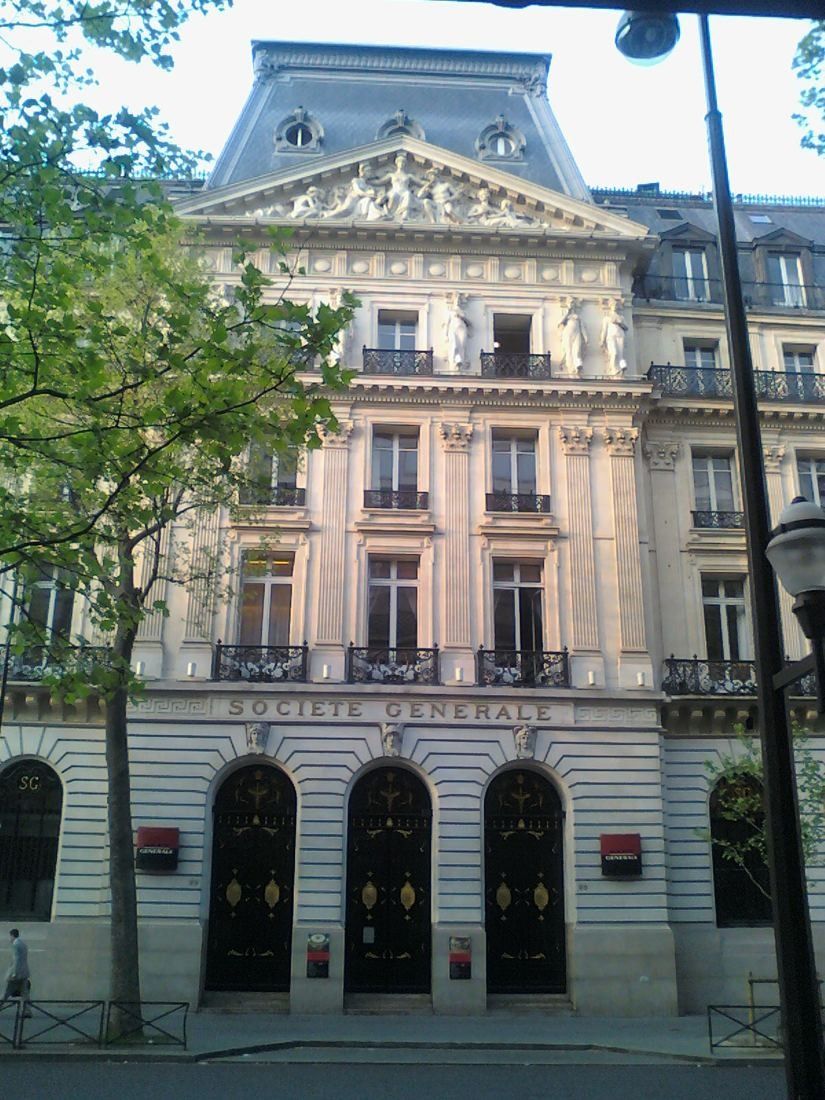 Société Générale: Tall stone facade with a sculpted pediment and arched doors, a lamp post in front