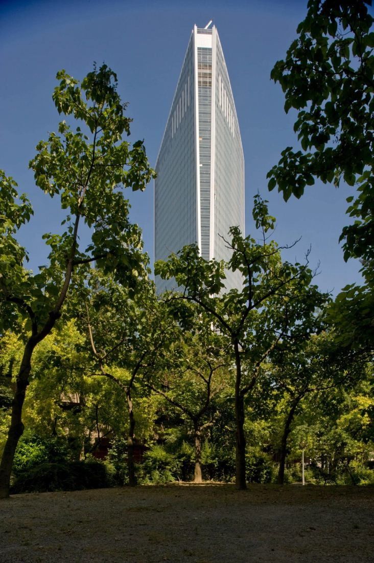 Société Générale: Top of a pointed glass tower framed by dark green trees