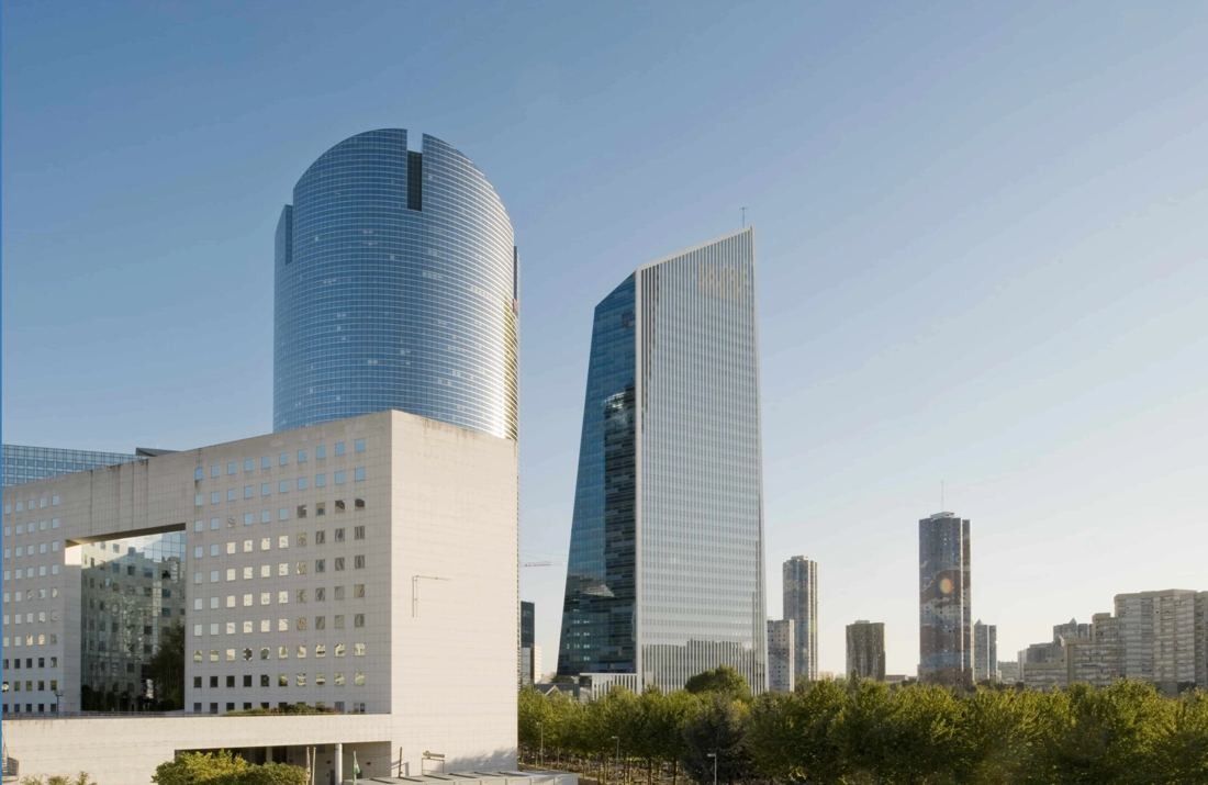 Société Générale: Two glass towers, one rounded and one angular, rising behind a white low-rise building at La Défense