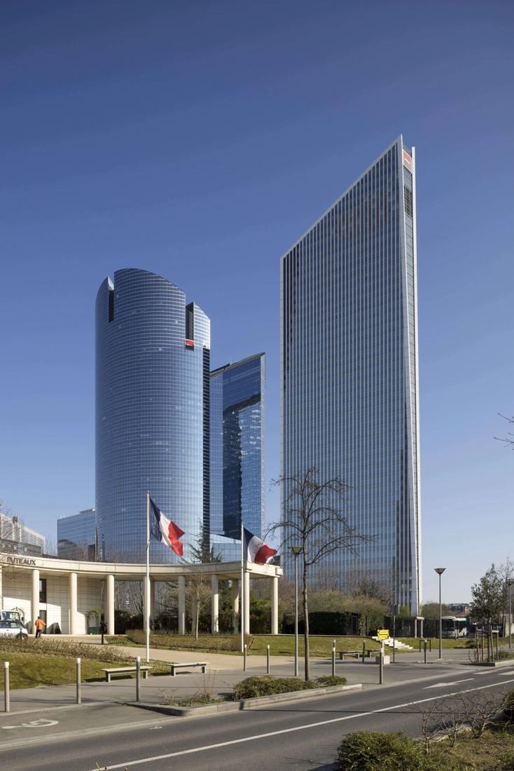 Société Générale: Two glass towers side by side under a clear blue sky, with a low entrance pavilion in front