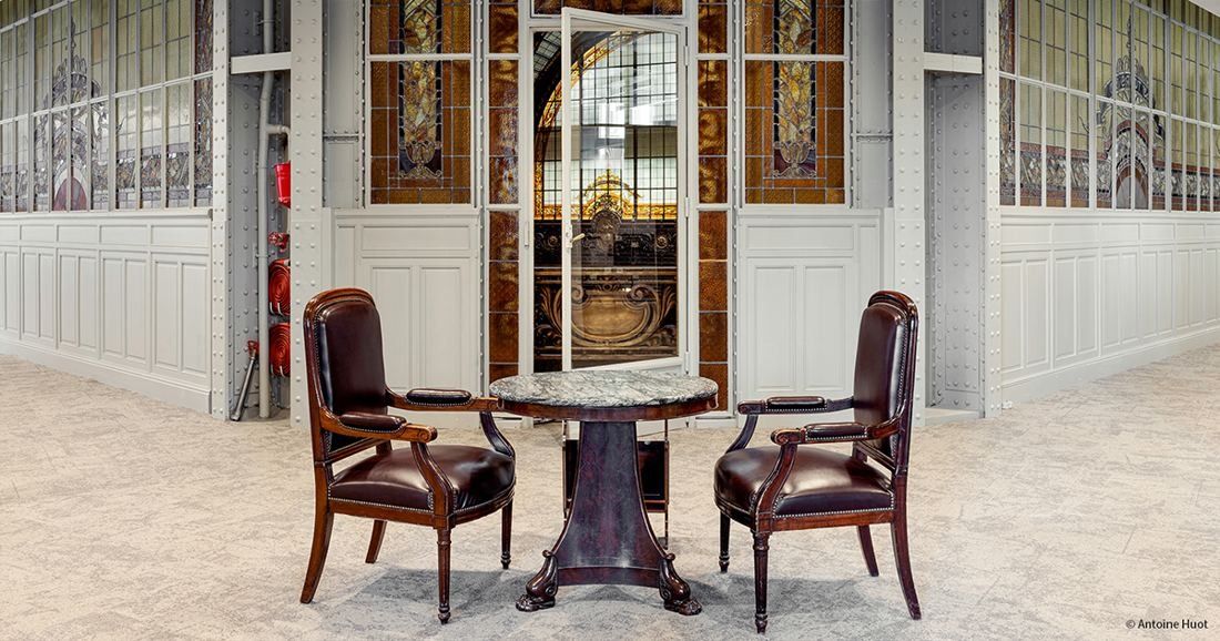 Société Générale: Two leather armchairs and a small round table in front of stained-glass panels in a bright white room