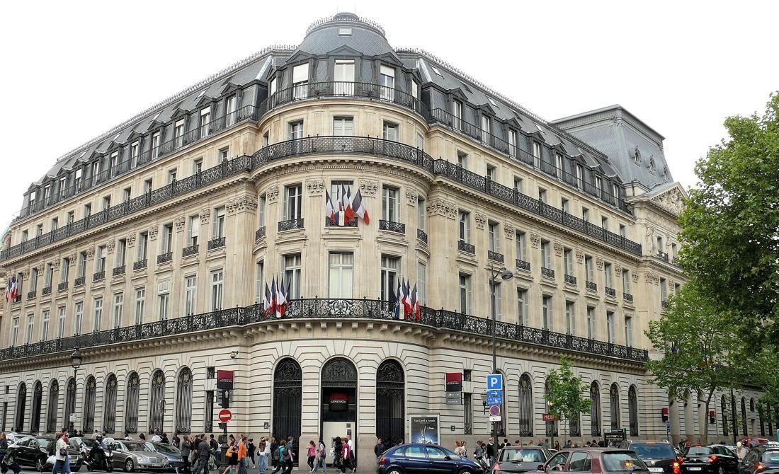 Société Générale: Wide view of the stone building with flags on its balconies and cars passing on the street