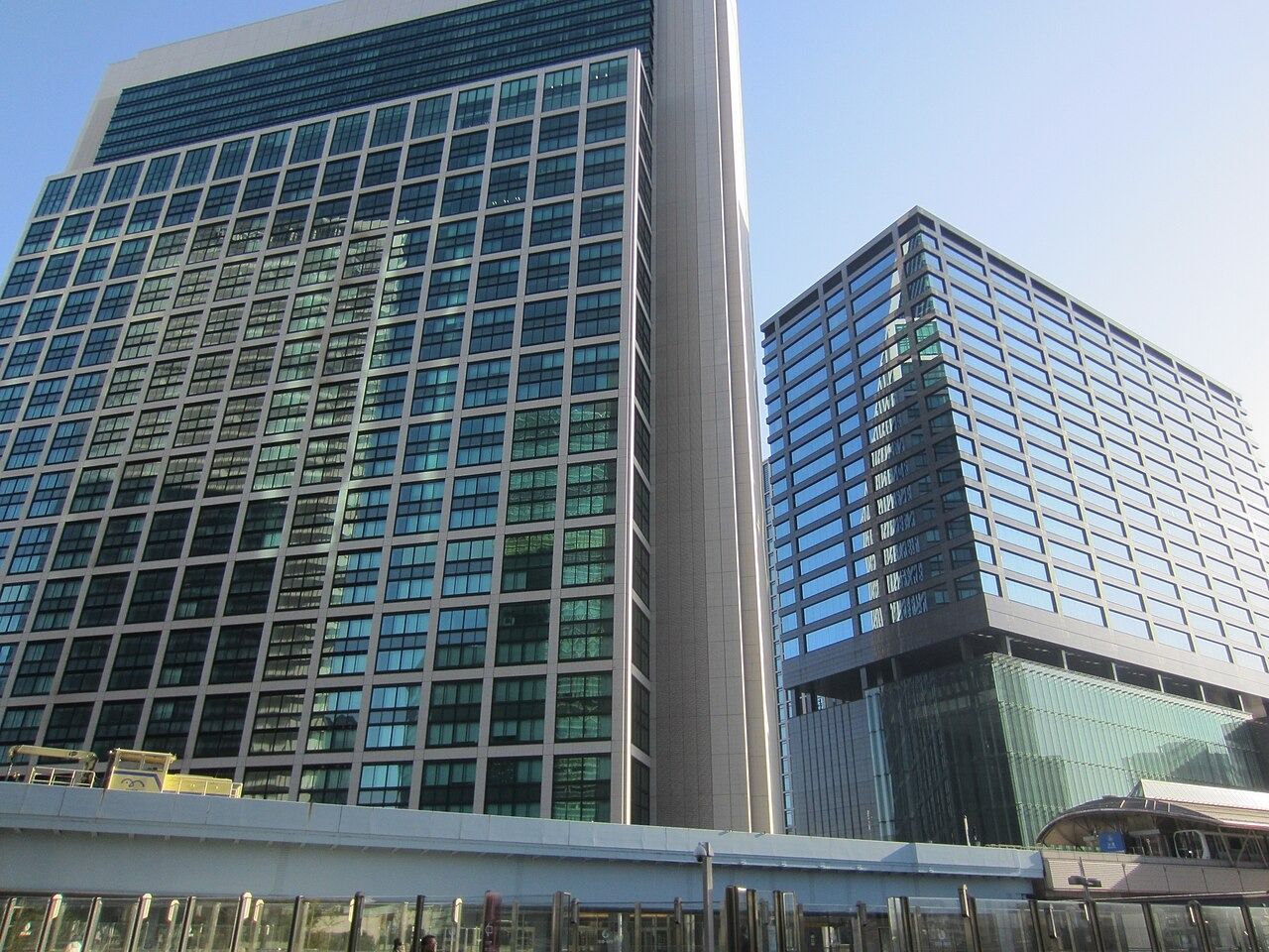 Two glass office towers beside an elevated walkway