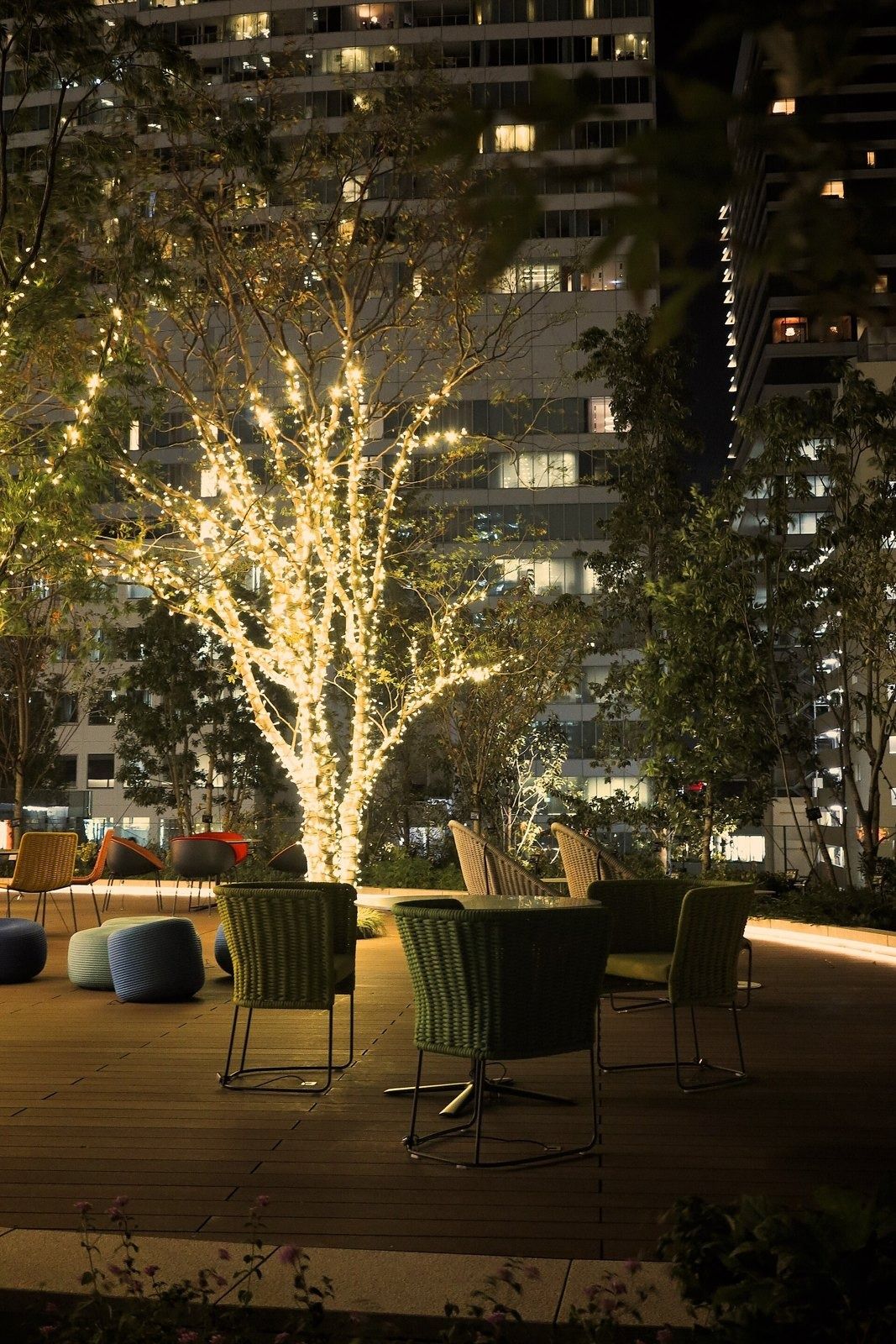 SoftBank Group: Lit tree among lounge chairs on a terrace at night