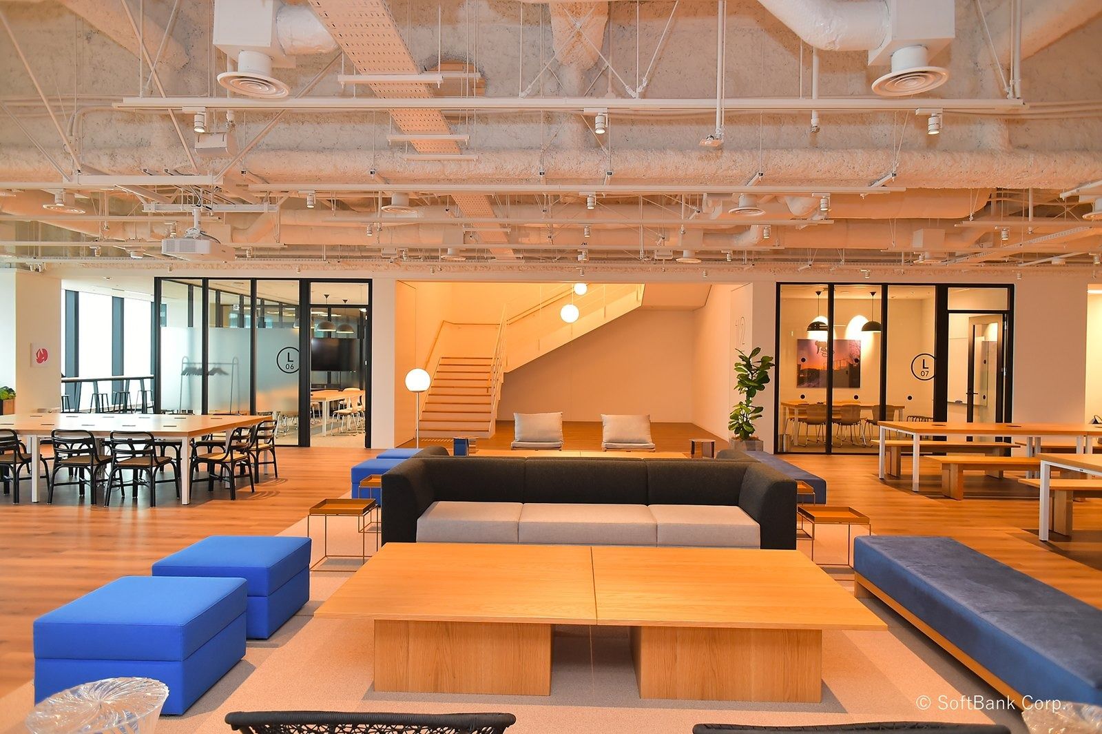 SoftBank Group: Open lounge with a wooden stair, blue ottomans and long tables