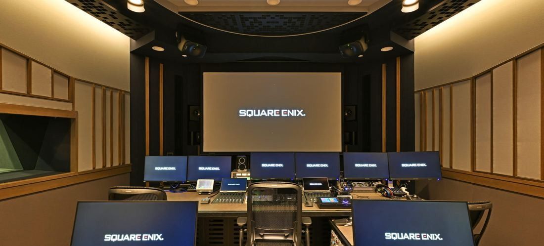 Square Enix: Dark studio room with a large screen, a row of monitors and a mixing desk