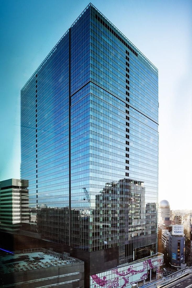 Square Enix: Glass office tower rising above a busy Shibuya street