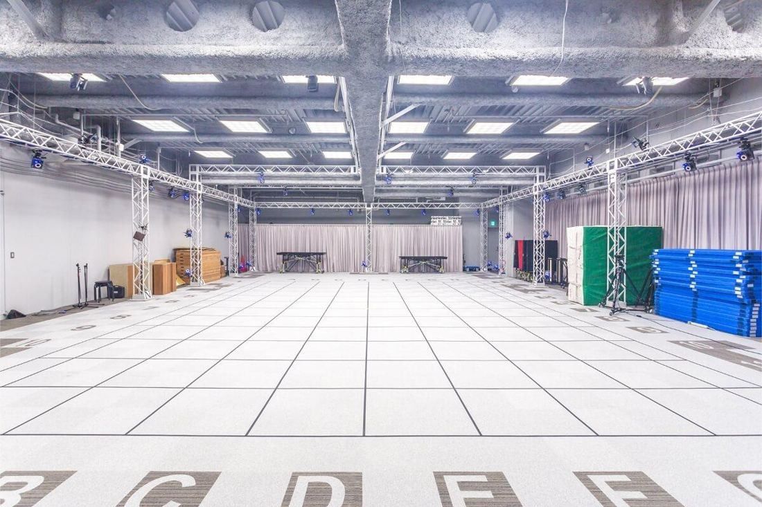 Square Enix: Large empty studio with a white floor grid, ceiling truss and camera rig