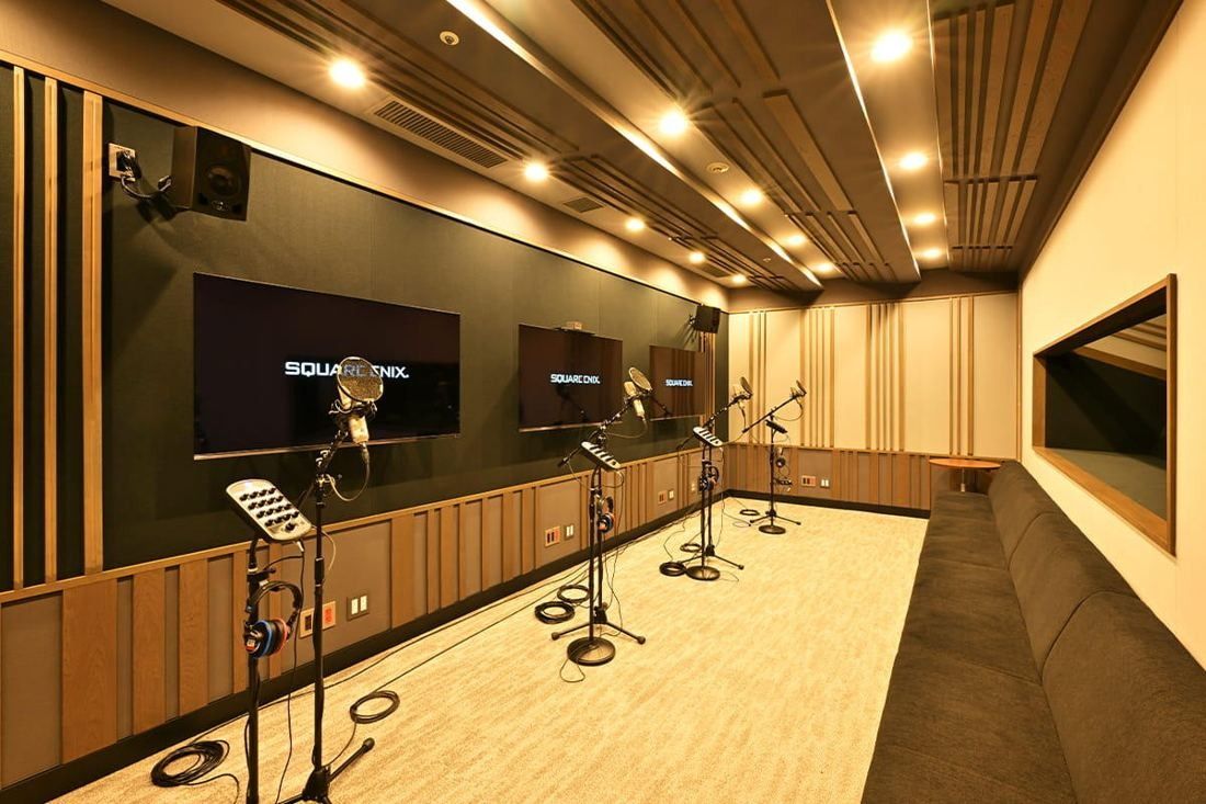 Square Enix: Long recording room with several microphones, wood panelling and screens