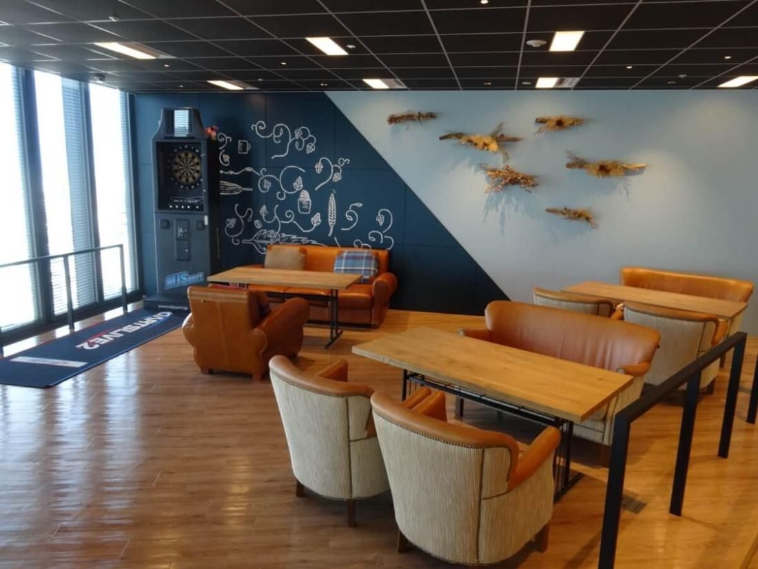 Square Enix: Lounge with orange leather chairs, wooden tables and a decorated blue wall