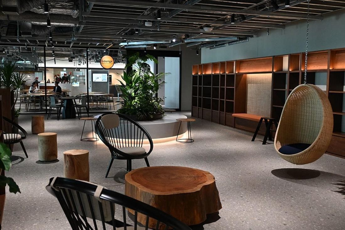 Square Enix: Lounge with stump tables, black chairs, a hanging wicker chair and plants