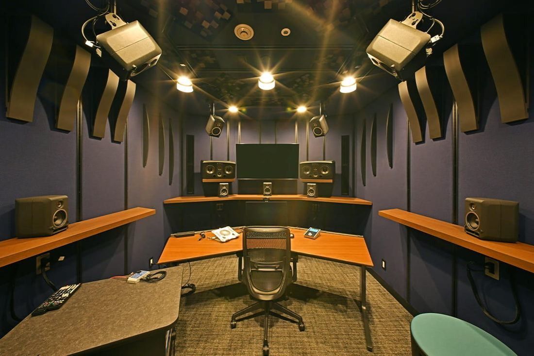 Square Enix: Mixing room with a curved desk, speakers and a screen under spotlights