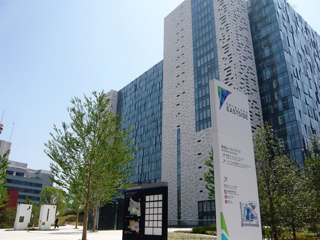 Square Enix: Office building with perforated panels and glass, trees and a site sign in front