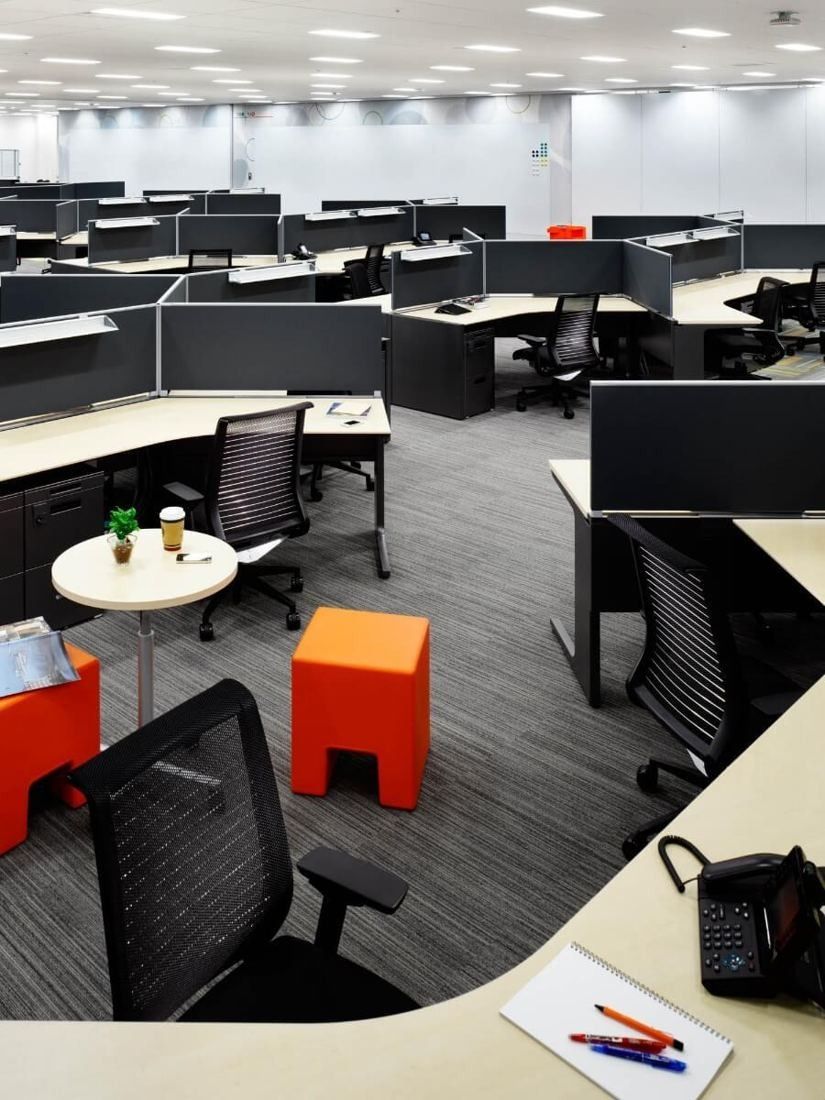 Square Enix: Open office with curved desk rows, monitors and a small round table with orange stools