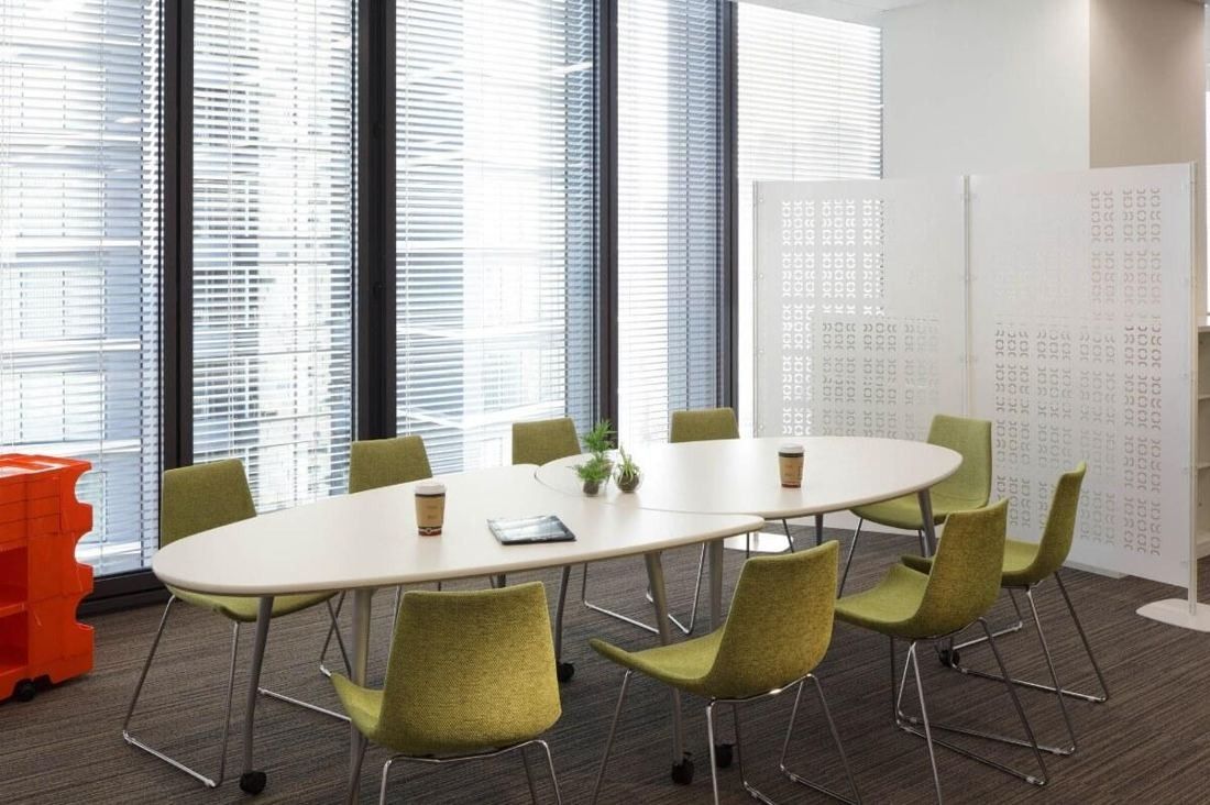 Square Enix: Oval meeting table with green chairs beside tall windows