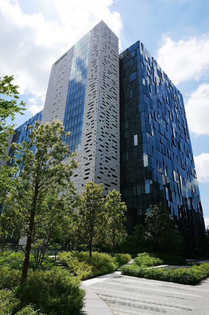 Square Enix: Tower with patterned white panels and blue glass above landscaped planting