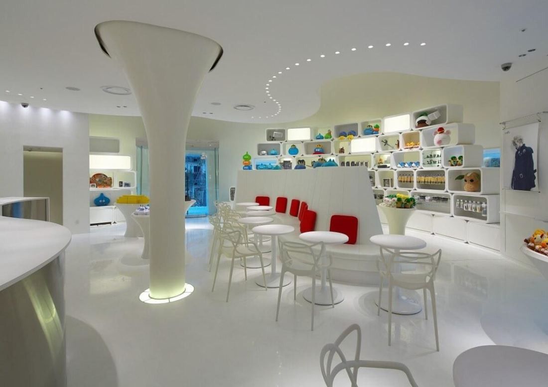 Square Enix: White shop-café interior with a sculptural column, round tables and display shelves