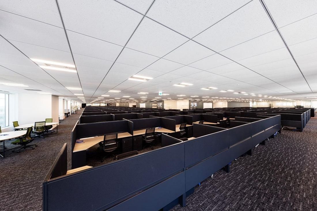 Square Enix: Wide office floor with long rows of desks and low partitions