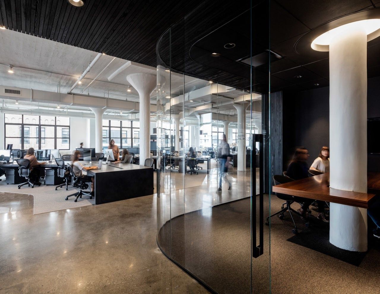 Squarespace: Glass-walled room with a white column beside an open office floor of desks and large windows