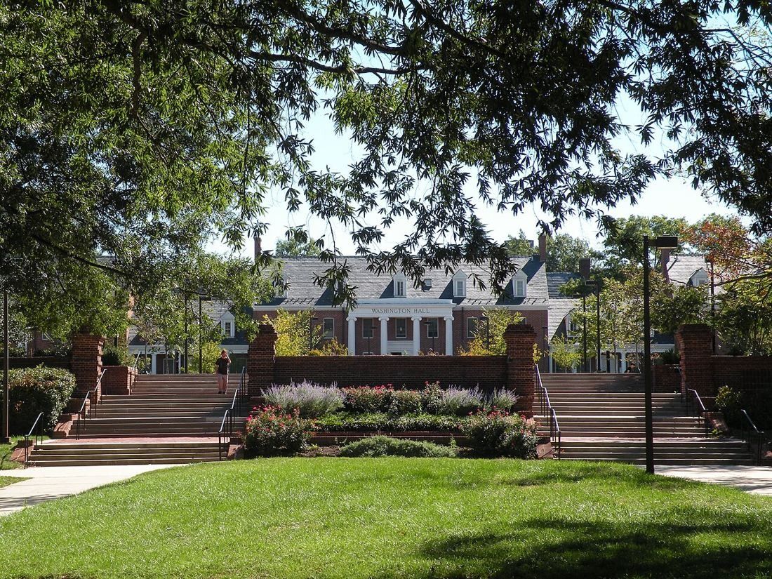 Brick residence hall behind a courtyard with steps and flower beds