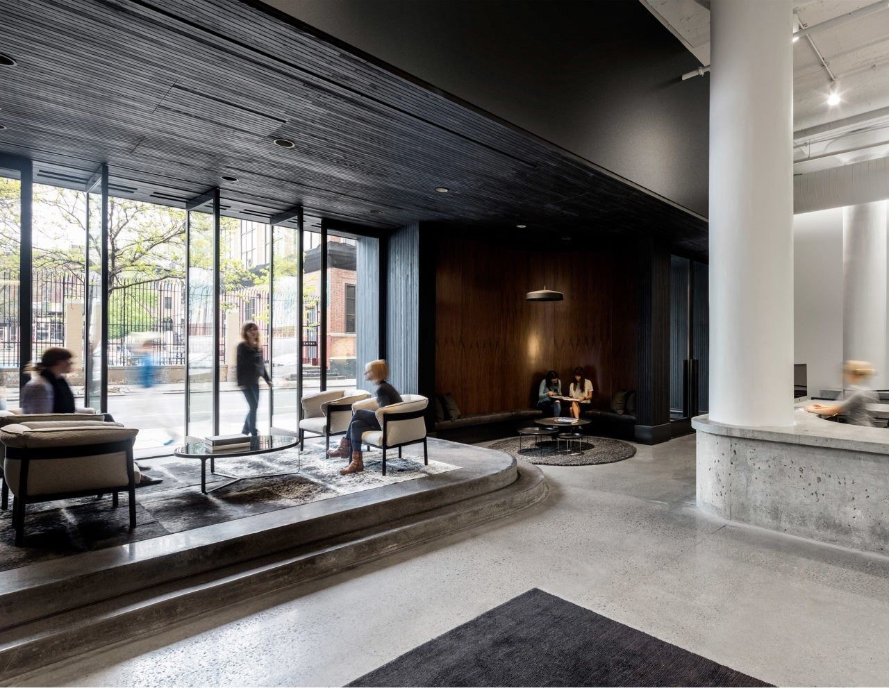 Squarespace: Lounge with low armchairs and a sunken seating area beside floor-to-ceiling windows onto the street
