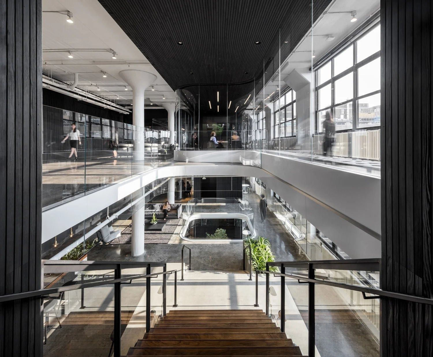 Squarespace: View down through a multi-storey atrium with glass railings, white columns and trees on the lower floor