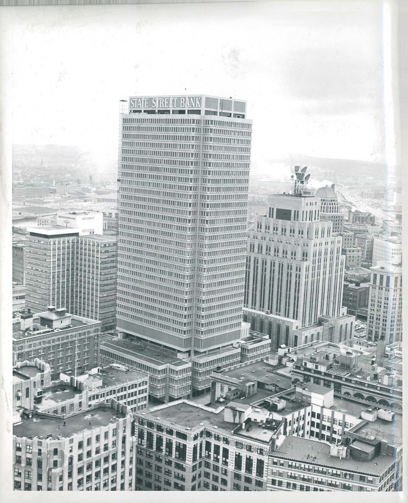 Black-and-white photo of a tall office tower among older buildings