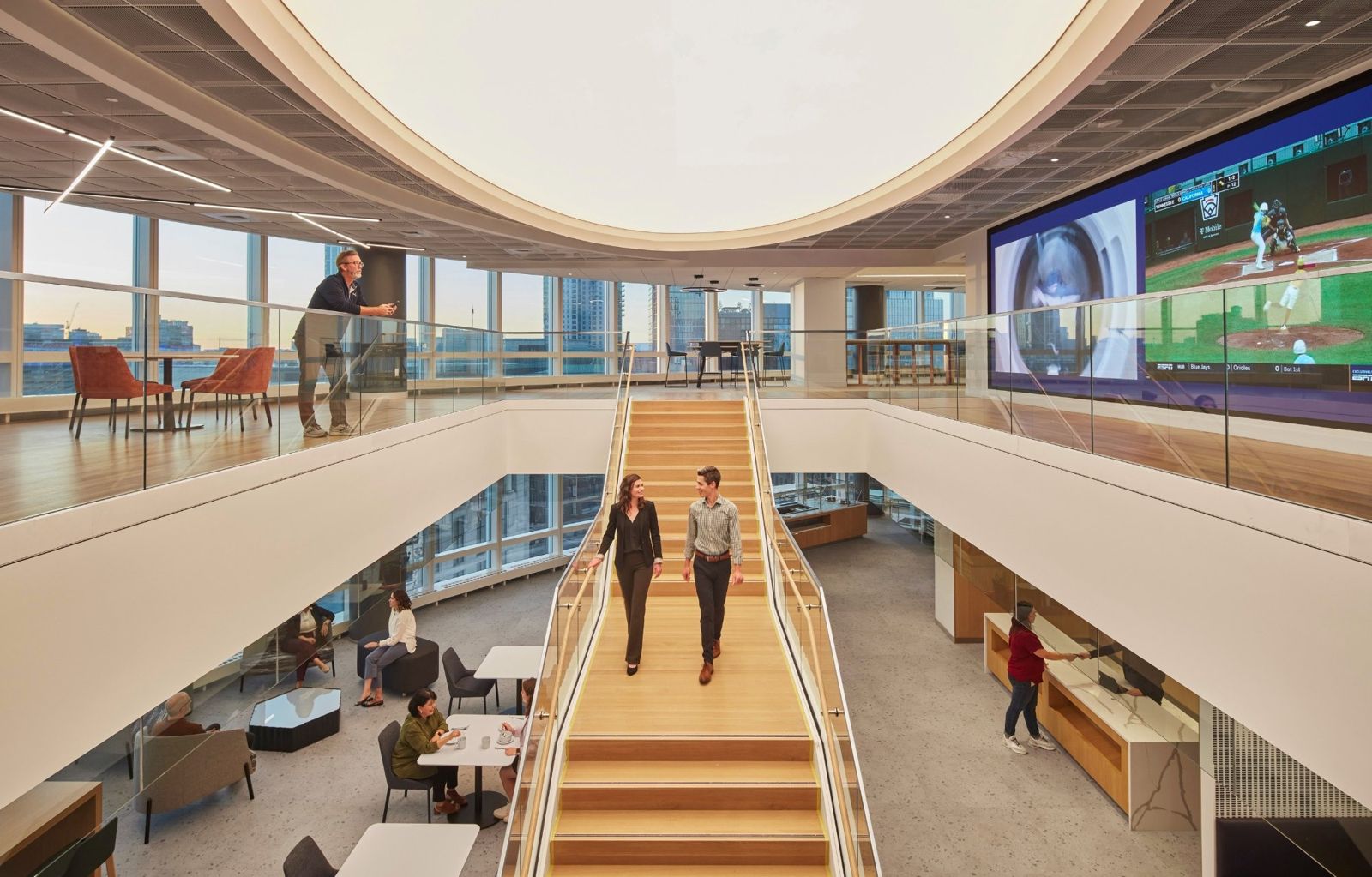 Wide open stair rising between two floors under a big media wall