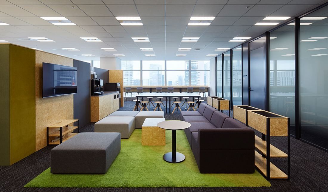 Sumitomo Corporation: Casual seating area with sofas on green carpet and wooden shelves