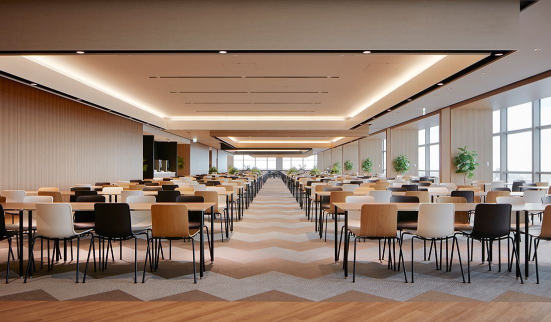 Sumitomo Corporation: Long room filled with rows of tables and mixed chairs on a zigzag-patterned floor
