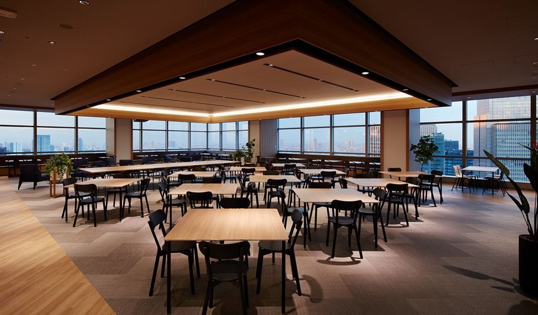 Sumitomo Corporation: Lounge with wooden tables and chairs under a dark wood canopy by the windows